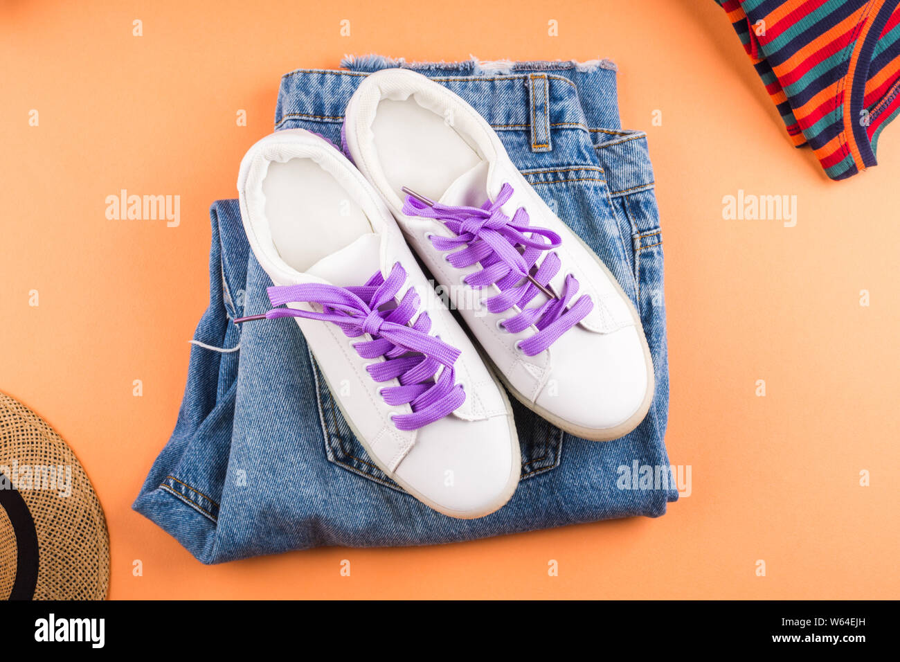 Fashion flat lay with folded jeans, white sneakers, striped t-shirt on  orange background. Back to school shopping concept Stock Photo - Alamy